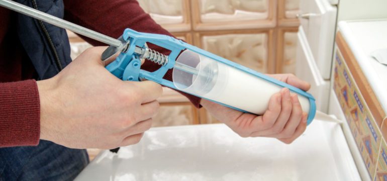 Man caulking windows on his November to-do list.