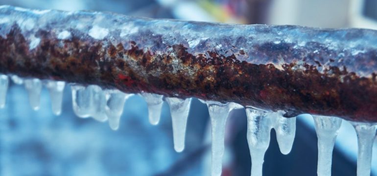Many small icicles on a frozen pipes during the winter.