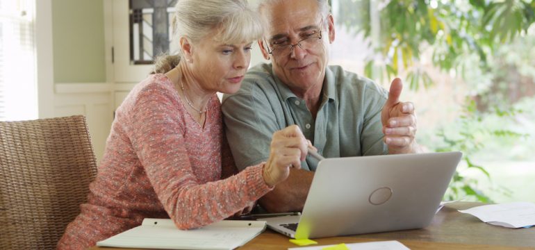 Senior couple using laptop to browse an online real estate marketplace looking to buy a home.