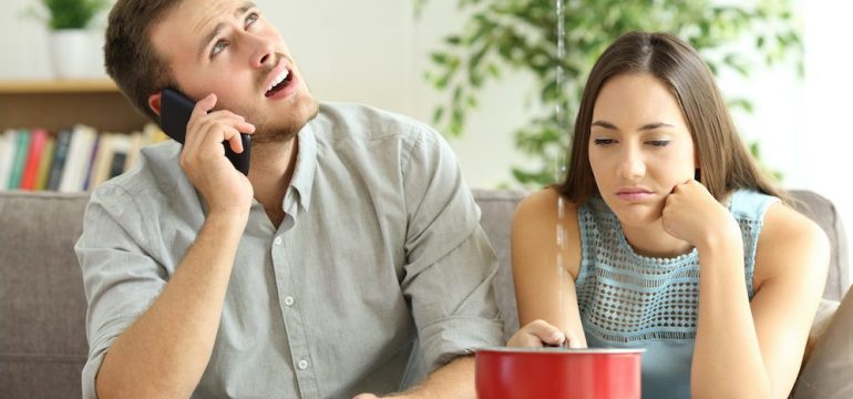 Couple dealing with buyer's remorse while calling insurance company for help with home leaks.