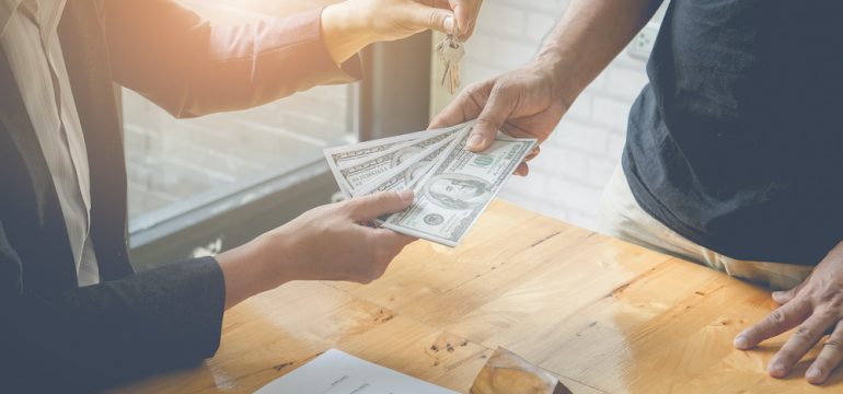 Agents are giving house keys of customer and holding dollars that represent real estate transfer fees.