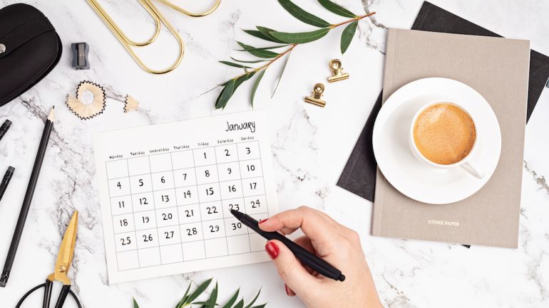 Desktop with calendar for January and office supplies. Home office, social media blog, schedule, planning concept.
