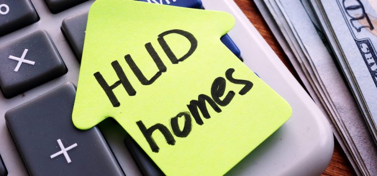 Section 8 HUD homes written on house shaped paper on top of a calculator.