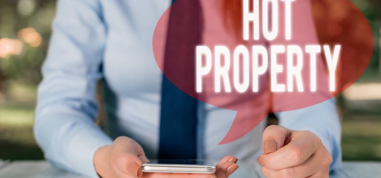 Male holding a calculator trying to figure out how to buy a house before you sell in a seller's market with the words hot property across photo