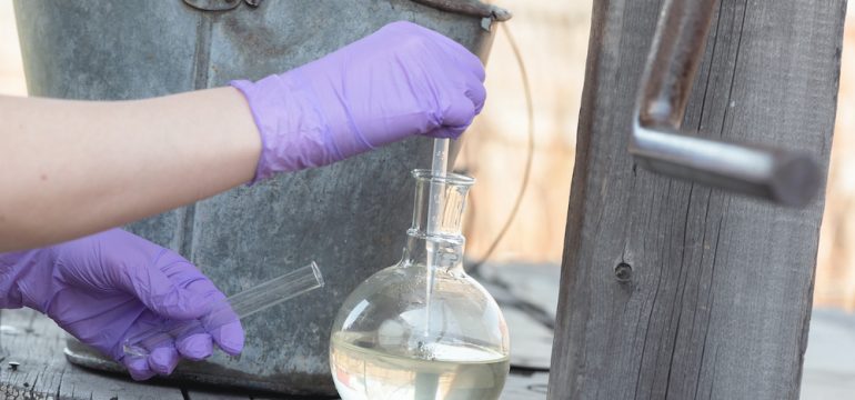 Testing private well water pollution concept. Scientist is taking a water sample for the test close up.