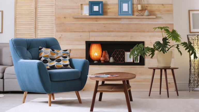 Cozy apartment with rental furniture. There is a blue armchair and coffee table in the foreground.