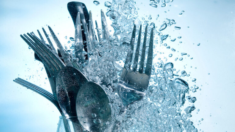 Washing kitchenware in dishwasher with clear water on bubbles background.