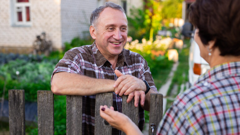 Airbnb hosting neighbors. A middle-aged man and his neighbor chatting near the fence between homes.