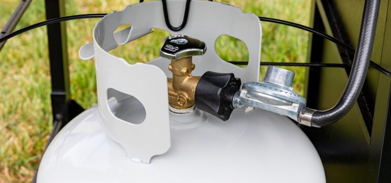 Propane tank with hose and regulator for BBQ grill. Grilling safety, propane tanks equipment inspection and storage.
