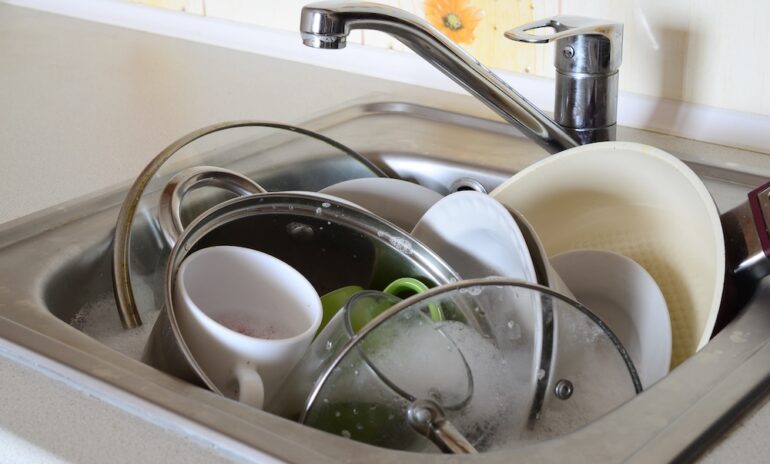 Soaking dishes and unwashed kitchen utensils in a full kitchen sink.