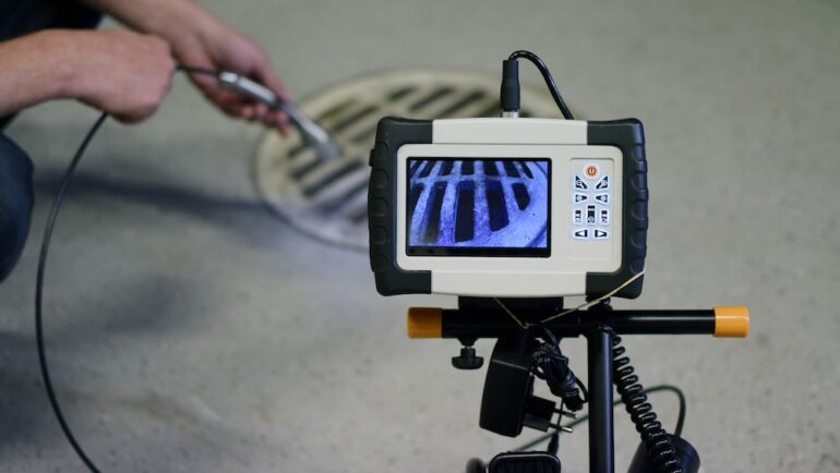 A home inspector using a borescope to view a shower drain.